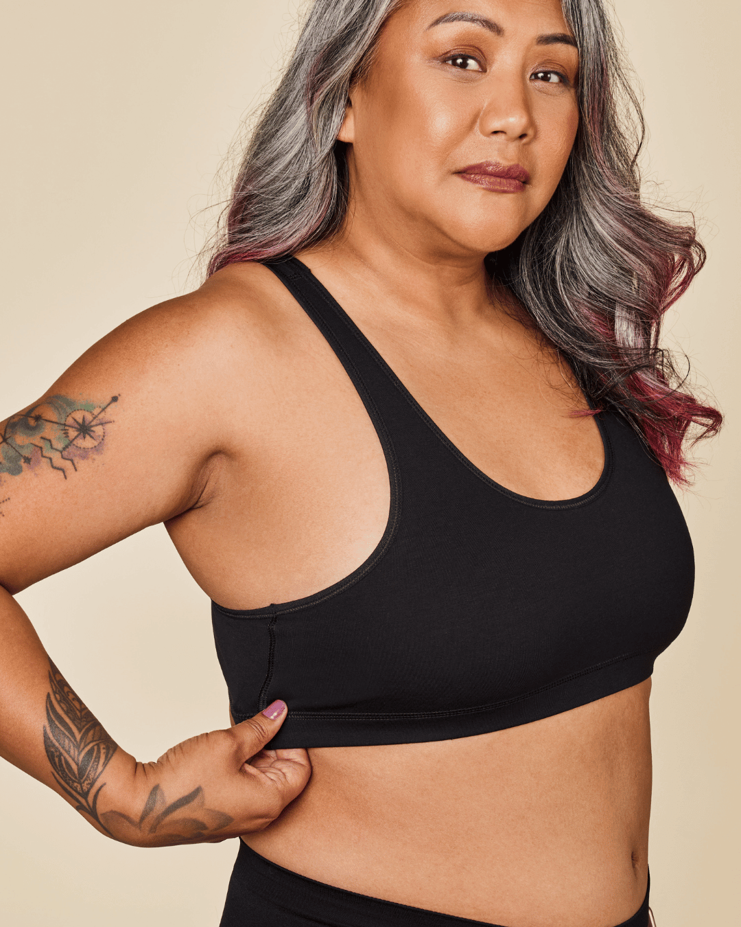 Woman wearing a black sports bra against a beige background