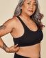 Woman wearing a black sports bra against a beige background