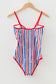 Striped swimsuit with red, white, and blue pattern on a hanger against a white background