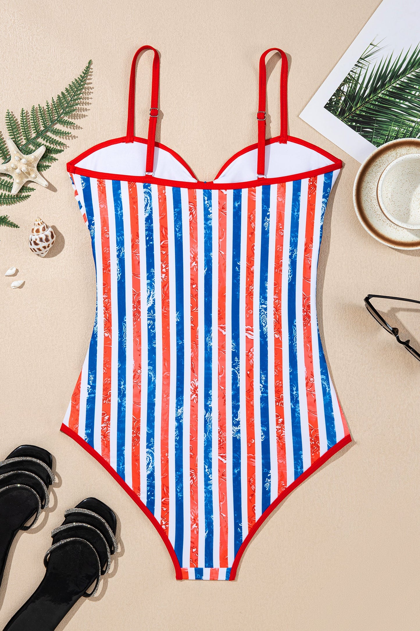 Striped swimsuit with red, white, and blue pattern on a beige surface with decorative items.
