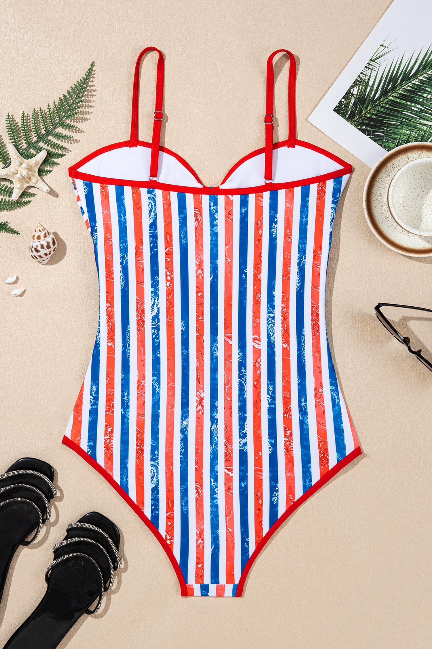 Striped swimsuit with red, white, and blue pattern on a beige surface with decorative items.