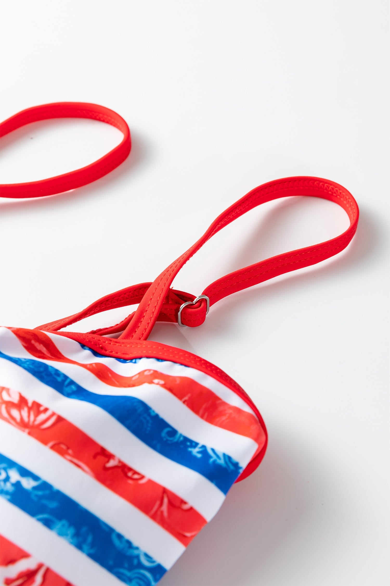 Red, white, and blue striped bag with a red strap on a light background