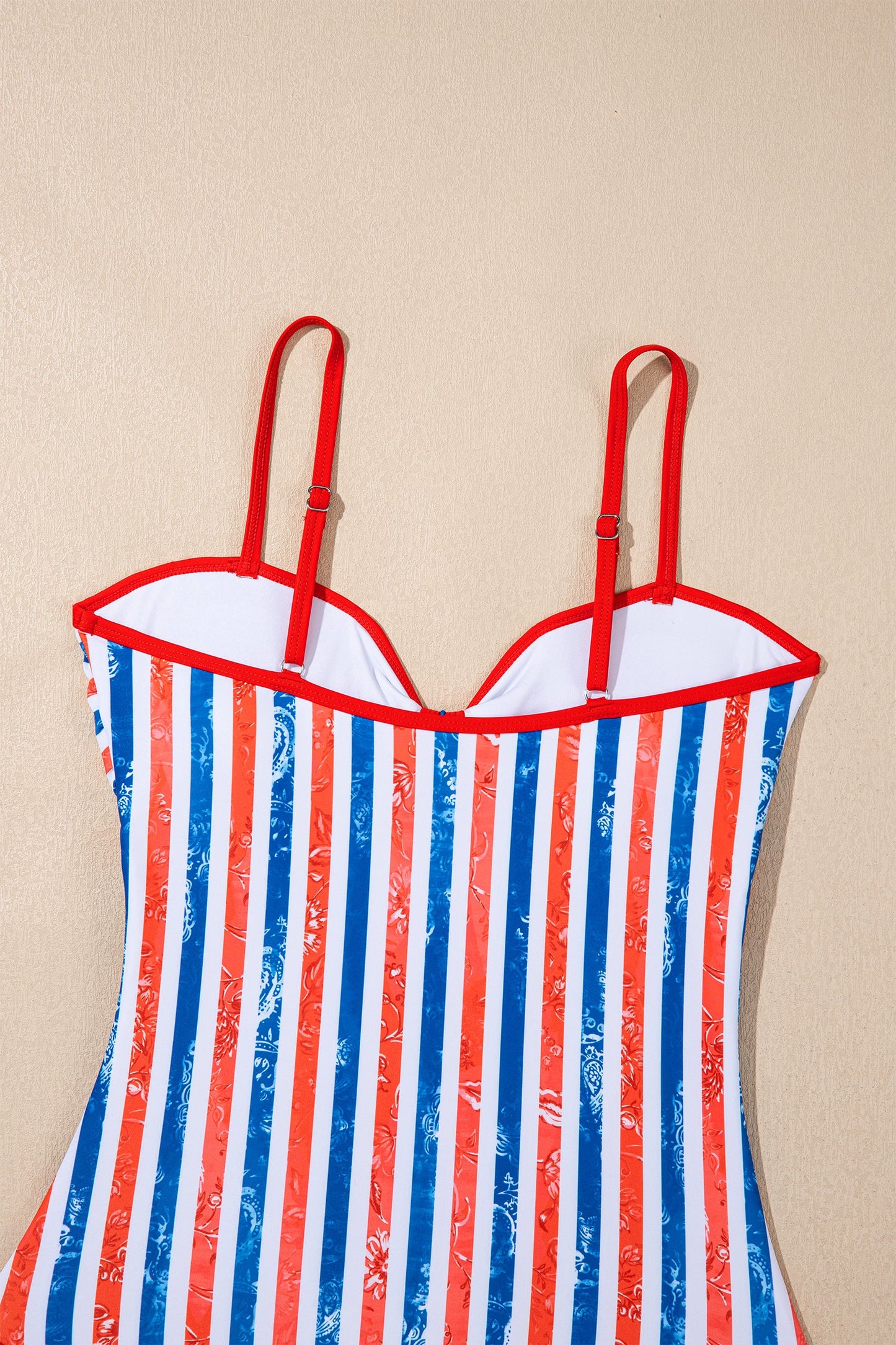 Striped swimsuit with red, white, and blue pattern on a beige background
