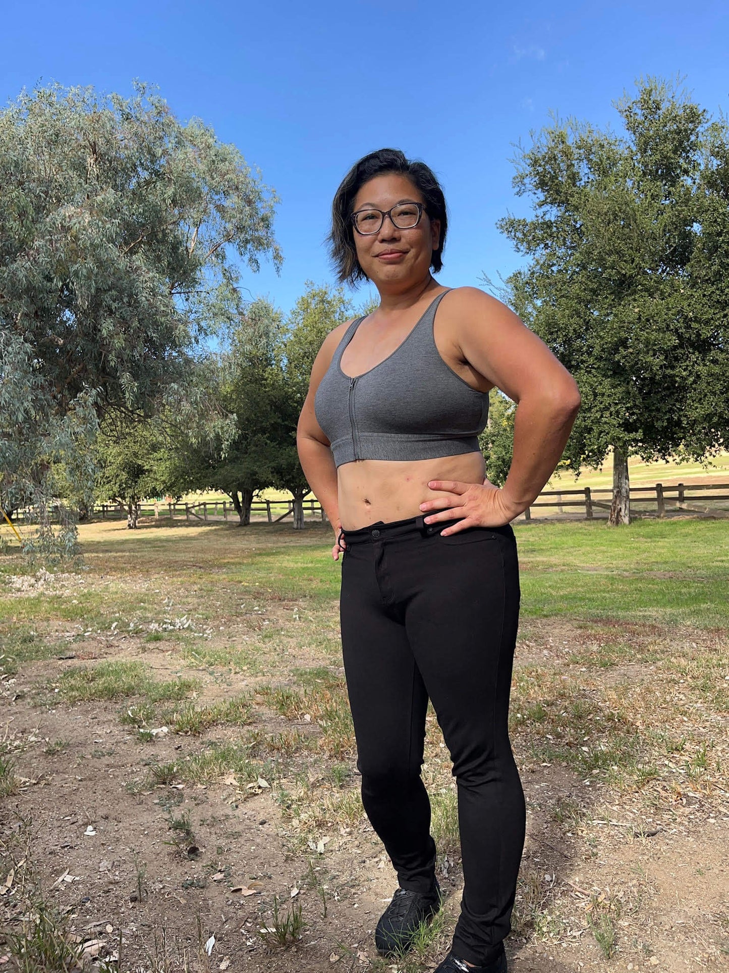 Person wearing athletic gear standing outdoors with trees and a clear sky in the background