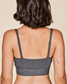 Person wearing a gray bralette on a beige background