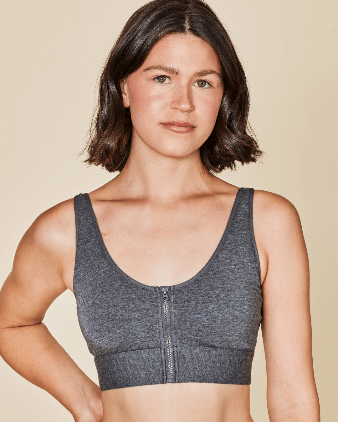 Woman wearing a gray sports bra against a beige background